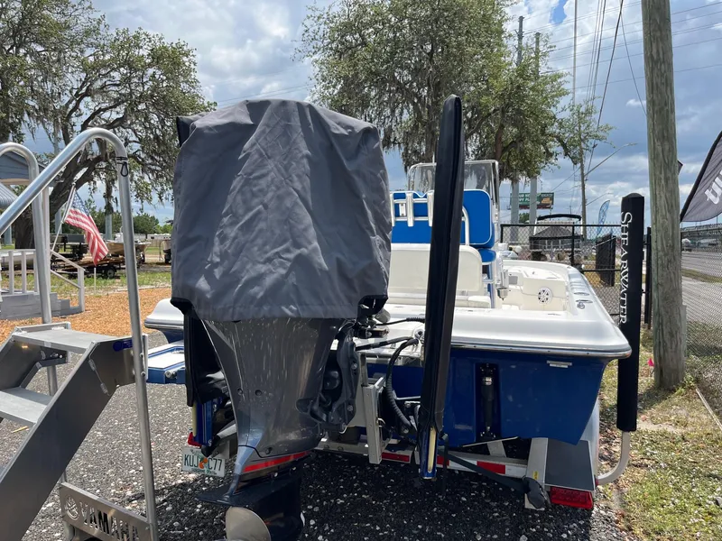 Slide: The Image of 2017 ShearWater 23LTZ boat with covered motor, parked outdoors near trees and a fence. - 17