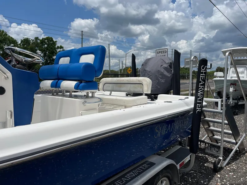 Slide: The Image of 2017 ShearWater 23LTZ boat with blue seating, parked on a trailer under a cloudy sky. - 18