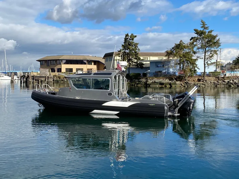 Slide: The Image of 2021 Life Proof 25 Full Cabin boat on calm water, with buildings and trees in the background. - 34