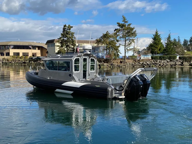 Slide: The Image of 2021 Life Proof 25 Full Cabin boat on calm water, with trees and buildings in the background. - 35