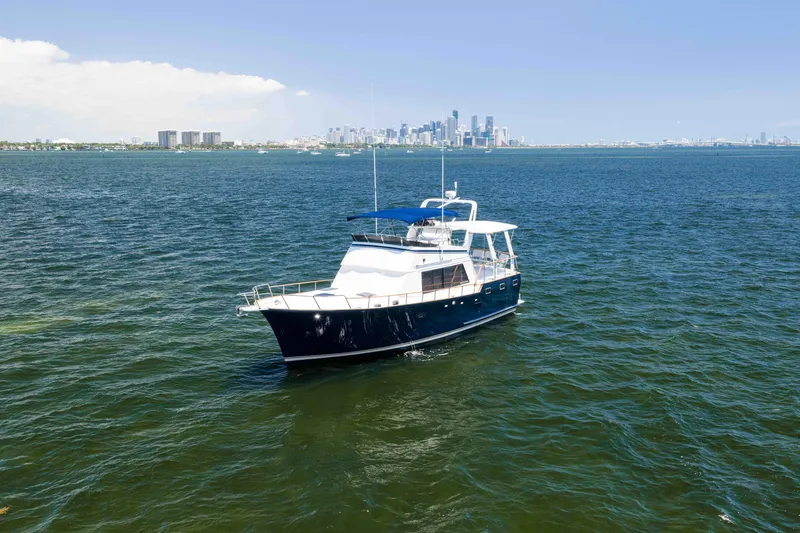 Slide: The Image of 1983 Sea Ranger 45 Sundeck yacht on open water with city skyline in background. - 17