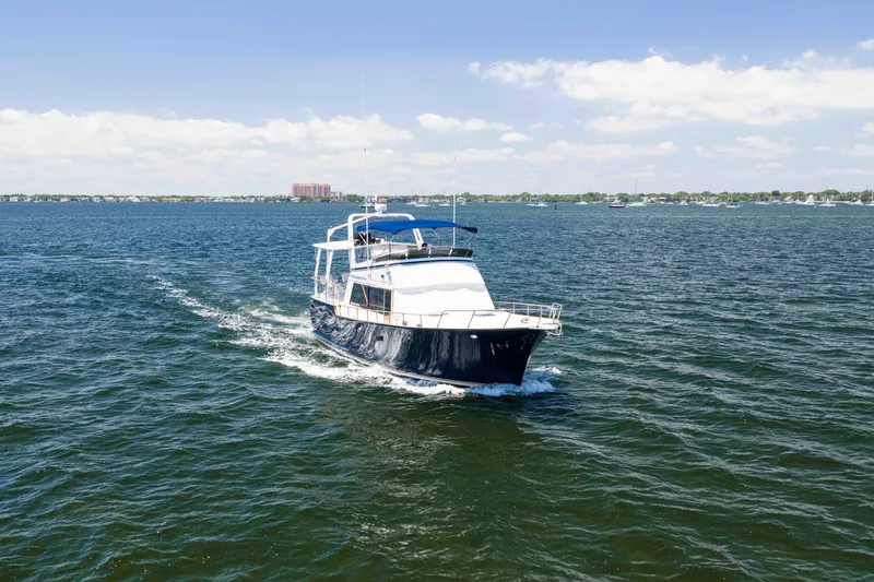 Slide: The Image of 1983 Sea Ranger 45 Sundeck cruising on open water under a clear blue sky. - 19