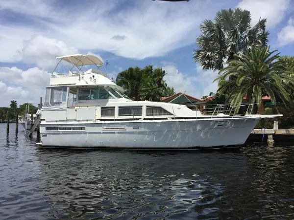 The Image of 1987 Bertram Motoryacht docked by palm trees under a partly cloudy sky. - 0