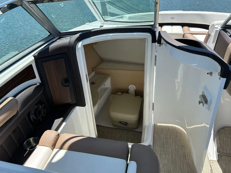 Slide: The Image of 2015 Cobalt 24SD boat interior with open cabin door, revealing compact restroom. - 5