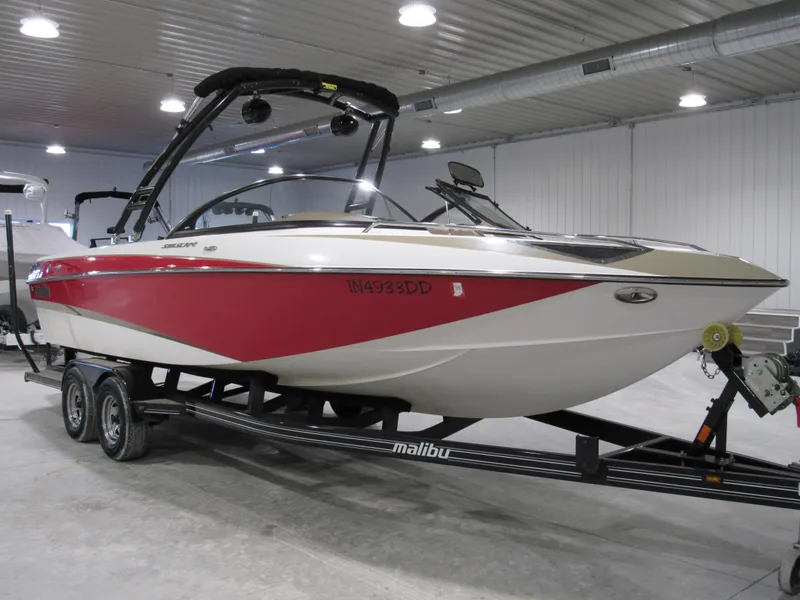 Slide: The Image of 2007 Malibu Sunscape 247 LSV boat with red and white design on a trailer indoors. - 1