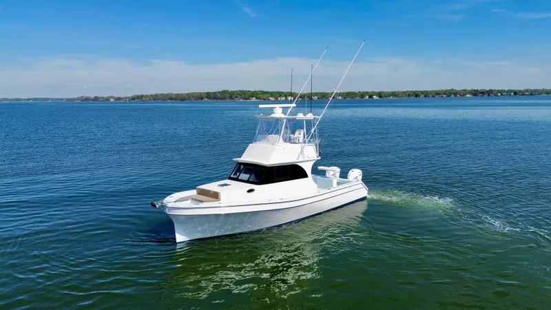 Slide: The Image of 2023 Millennium Marine NuWave 37 boat cruising on a calm lake under a clear blue sky. - 0