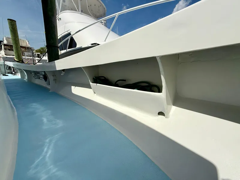 Slide: The Image of 2023 Millennium Marine NuWave 37 boat deck with storage compartments, blue flooring, and white railing. - 23