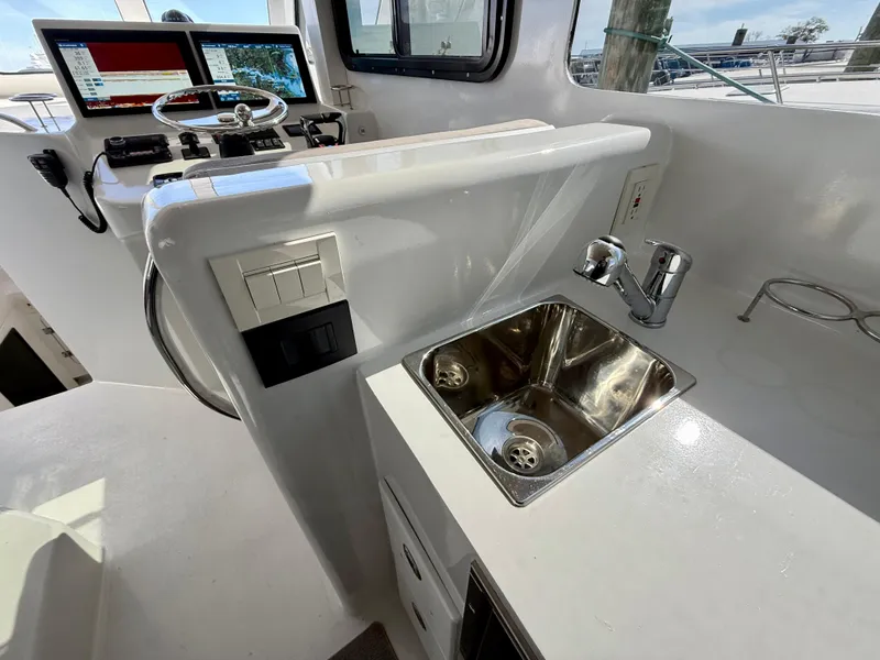 Slide: The Image of 2023 Millennium Marine NuWave 37 boat interior with steering console and stainless steel sink. - 30
