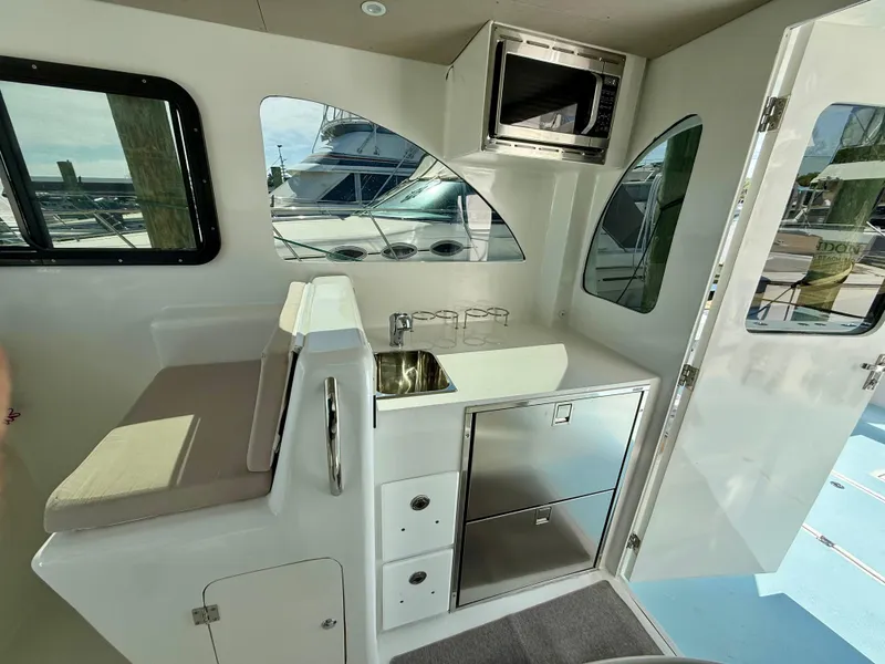 Slide: The Image of Interior of 2023 Millennium Marine NuWave 37, featuring kitchenette with sink, microwave, and seating. - 34