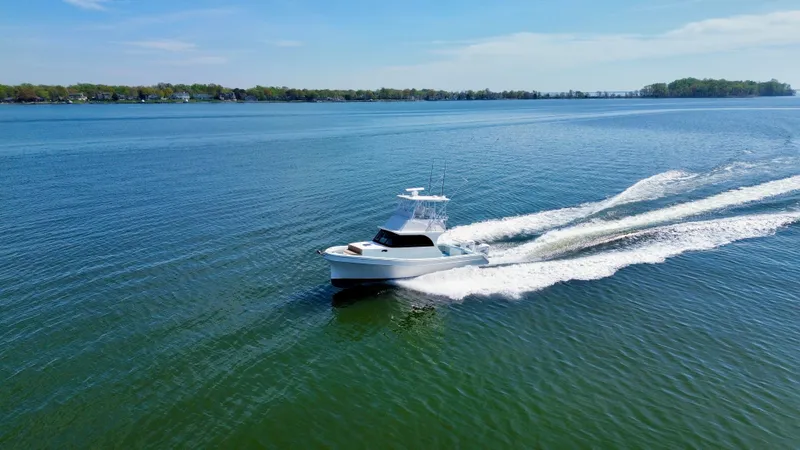 Slide: The Image of 2023 Millennium Marine NuWave 37 cruising on a serene lake under a clear blue sky. - 6