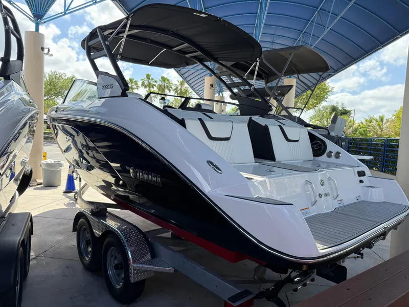 Slide: The Image of 2025 Yamaha Boats 222SD, sleek design, black and white, on trailer under canopy. - 4