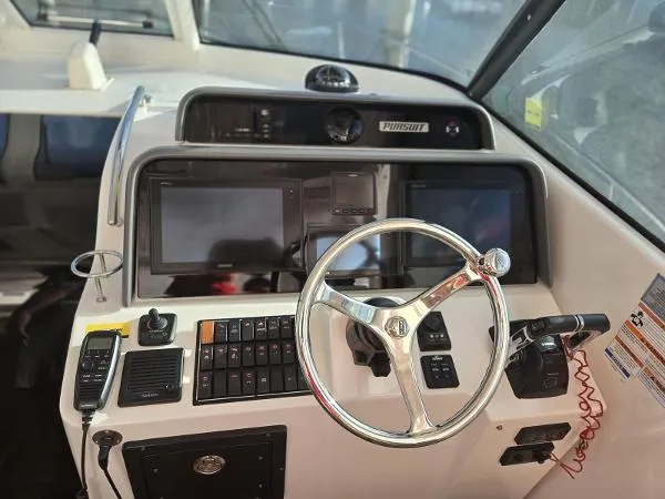 Slide: The Image of 2019 Pursuit OS 385 Offshore boat dashboard with steering wheel and navigation controls. - 21