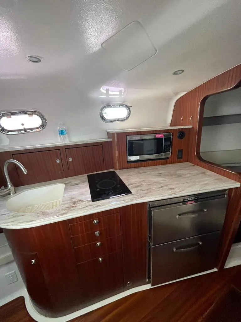 Slide: The Image of 2019 Pursuit OS 385 Offshore yacht kitchen with modern appliances and wood cabinetry. - 25