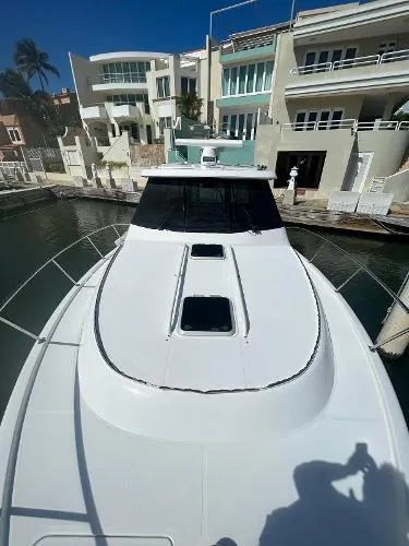 Slide: The Image of 2019 Pursuit OS 385 Offshore boat docked near modern waterfront homes. - 9