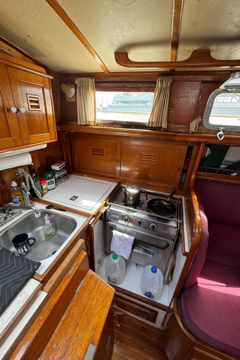 Slide: The Image of 1979 Cheoy Lee Bill Luders Clipper Ketch interior with compact kitchen and wooden cabinetry. - 11