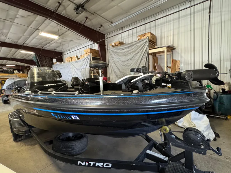 Slide: The Image of 2022 Nitro ZV21 boat in a garage, black with blue accents, on a trailer. - 2