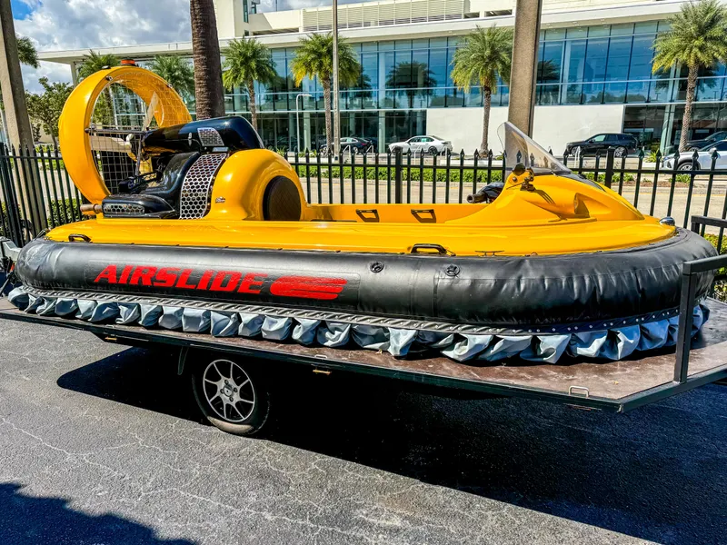 Slide: The Image of 2024 Airslide A33 airboat on trailer, yellow and black design, parked outdoors. - 0