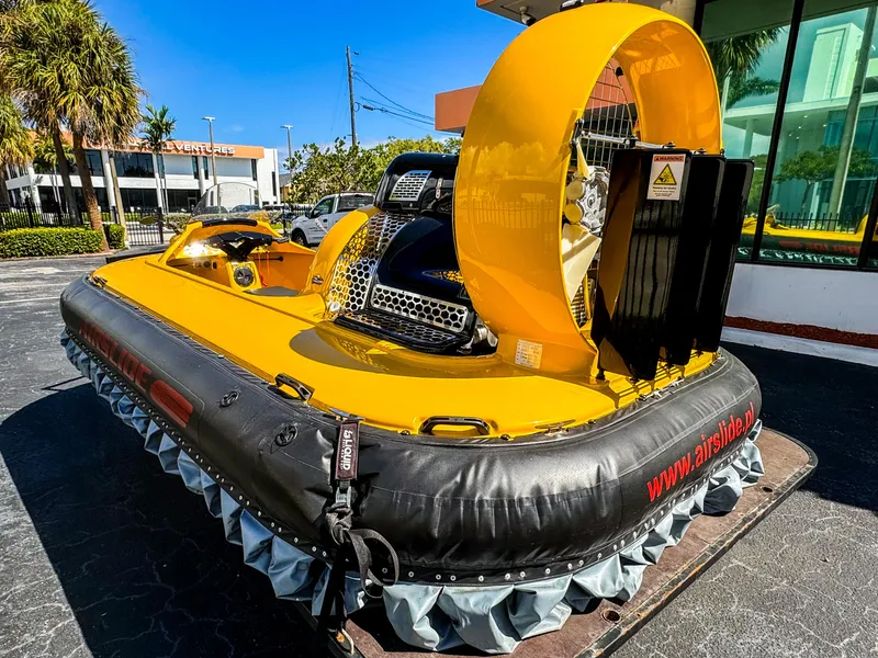 Slide: The Image of 2024 Airboat Airslide A33, yellow and black, parked outdoors on a sunny day. - 2