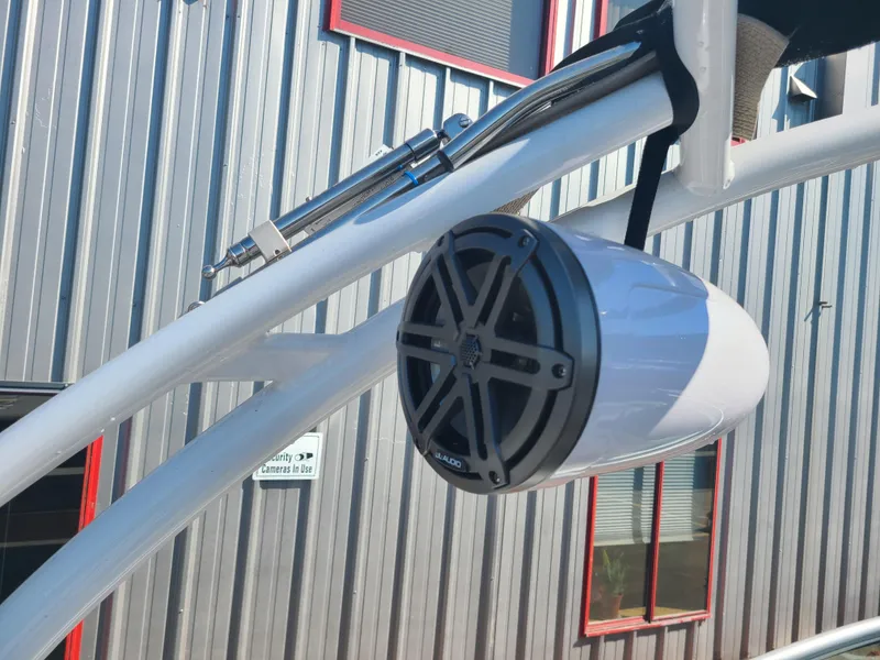 Slide: The Image of 2023 Four Winns H2 boat speaker mounted on a white frame, with a metal building background. - 14