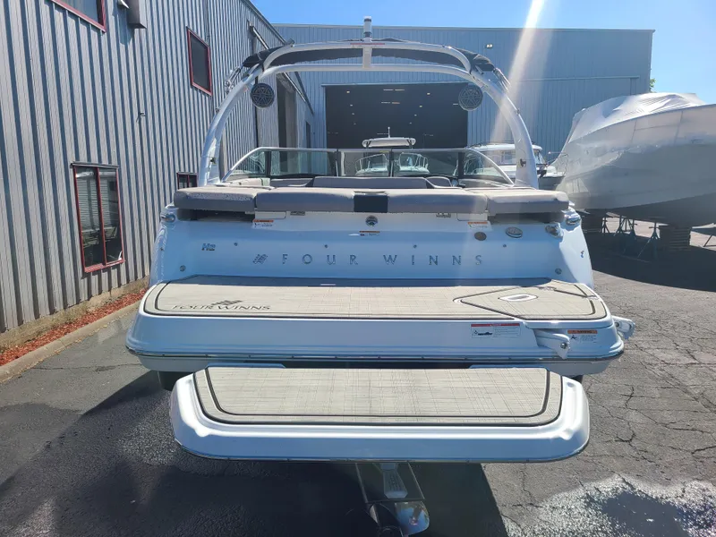 Slide: The Image of 2023 Four Winns H2 boat, rear view, parked outdoors near a warehouse. - 4