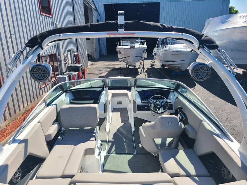 Slide: The Image of 2023 Four Winns H2 boat interior with modern seating and steering, docked near other boats. - 6