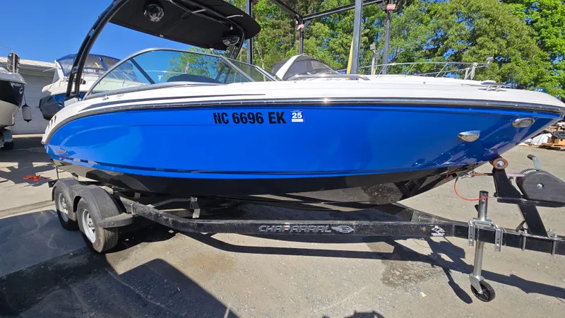 The Image of 2019 Chaparral 21 H2O Sport boat on trailer, vibrant blue hull, parked outdoors. - 0