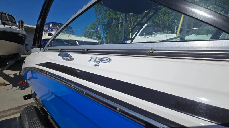 Slide: The Image of 2019 Chaparral 21 H2O Sport boat, blue and white exterior, docked under clear sky. - 5