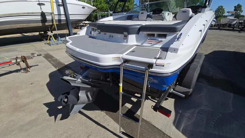 Slide: The Image of 2019 Chaparral 21 H2O Sport boat, rear view with ladder and propeller, parked on concrete. - 8