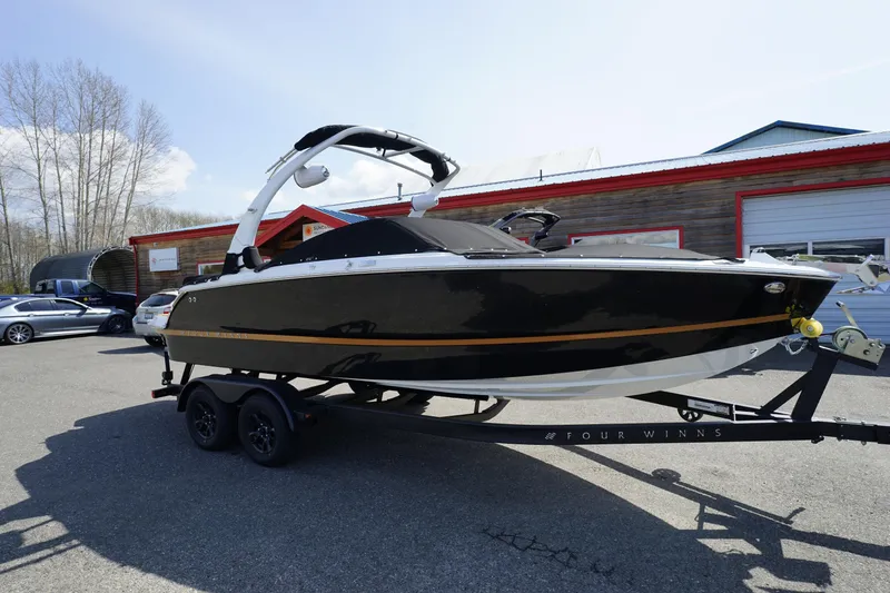 Slide: The Image of 2023 Four Winns H2 Surf boat on trailer, parked outdoors. - 0