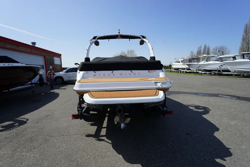 Slide: The Image of 2023 Four Winns H2 Surf boat, rear view, parked outdoors on a sunny day. - 1