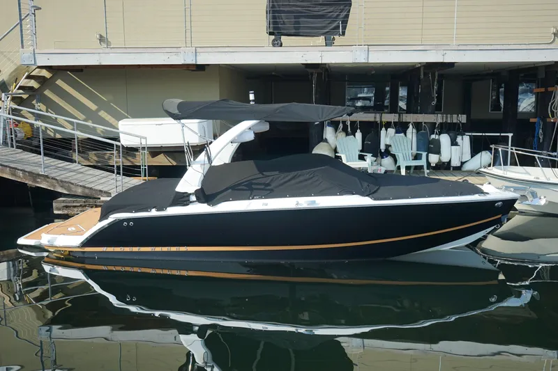 Slide: The Image of 2023 Four Winns H2 Surf boat docked, featuring sleek black design and covered seating area. - 2