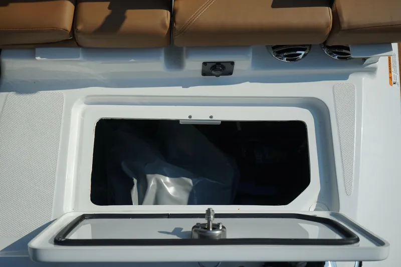 Slide: The Image of 2023 Four Winns H2 Surf boat storage compartment with open hatch and brown seating. - 22