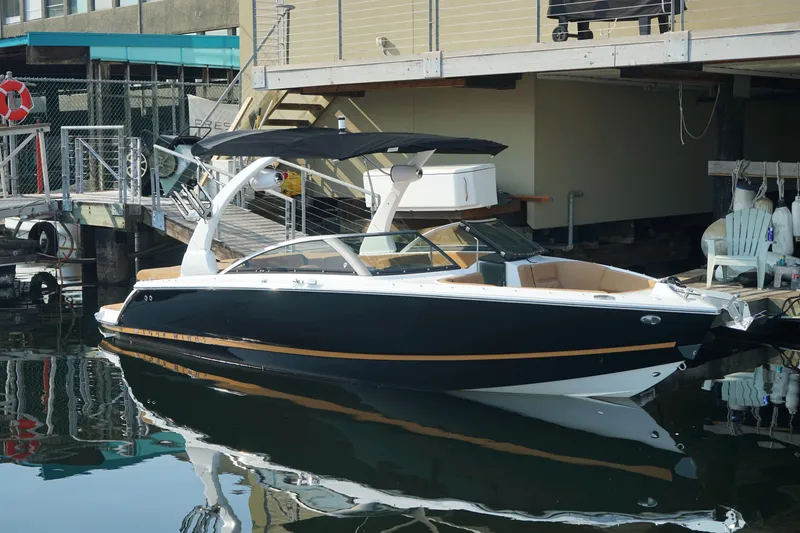 Slide: The Image of 2023 Four Winns H2 Surf boat docked, featuring sleek black and white design. - 6