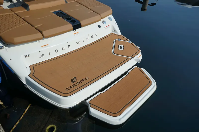 Slide: The Image of 2023 Four Winns H2 Surf boat with tan deck, docked on calm water. - 7