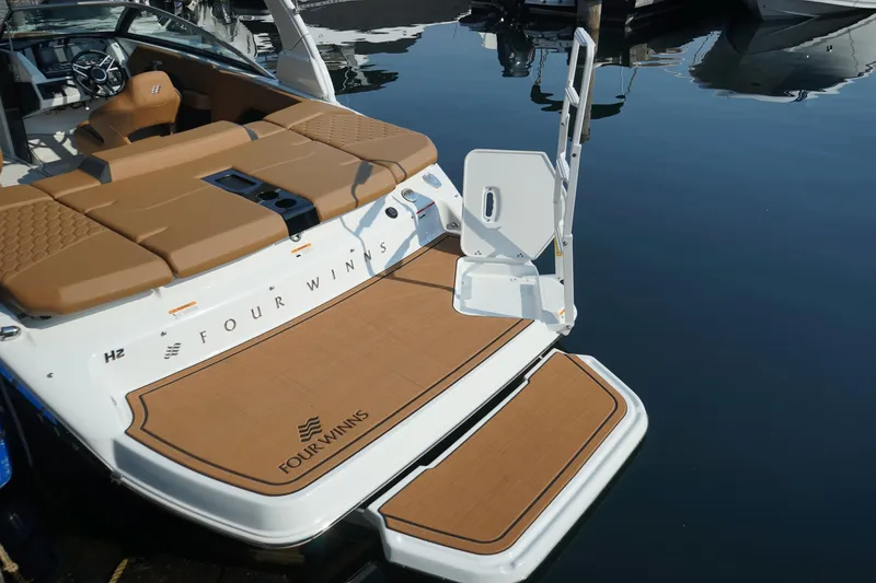 Slide: The Image of 2023 Four Winns H2 Surf boat with tan deck, docked on calm water. - 9