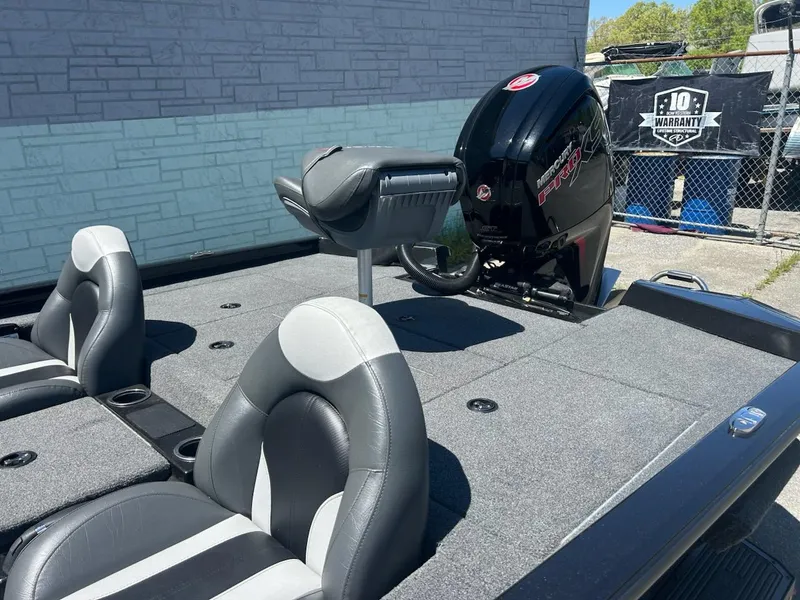 Slide: The Image of 2022 Vexus AVX1880 boat interior with seating and motor, parked outdoors. - 7