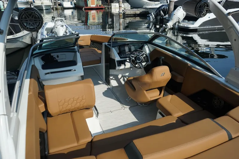 Slide: The Image of 2023 Four Winns H2 Surf boat interior with tan seating and modern dashboard. - 10