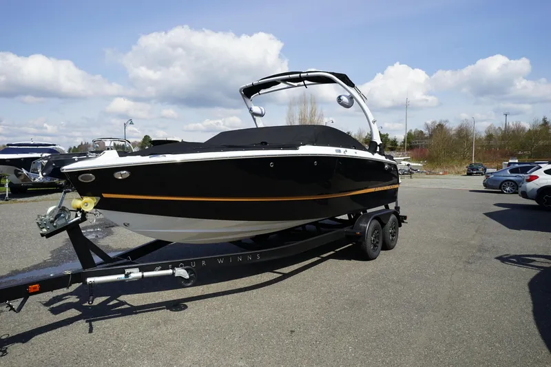 Slide: The Image of 2023 Four Winns H2 Surf boat on trailer under a cloudy sky. - 25