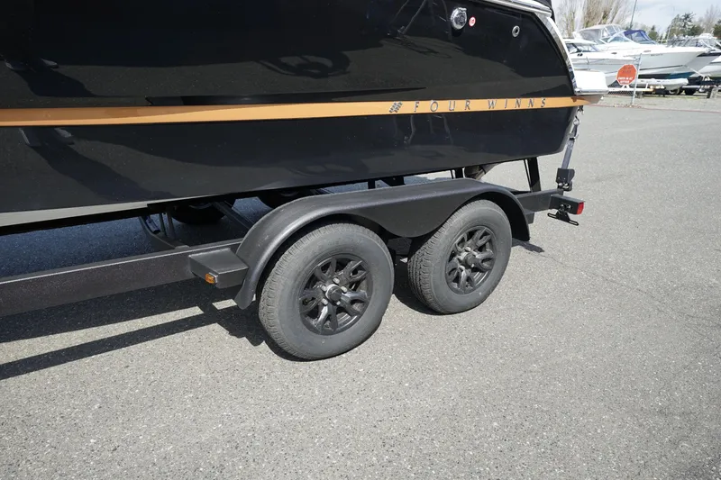 Slide: The Image of 2023 Four Winns H2 Surf boat on a dual-axle trailer, parked on asphalt. - 26