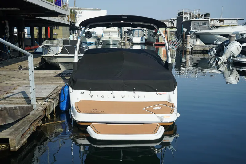 Slide: The Image of 2023 Four Winns H2 Surf boat docked at a marina, rear view. - 4
