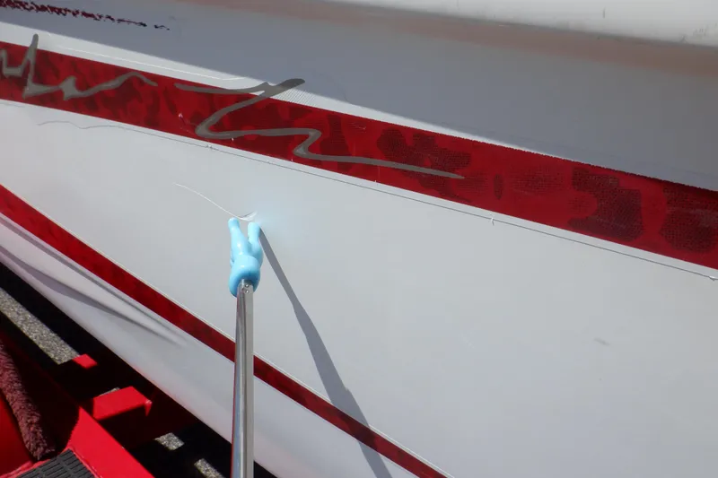 Slide: The Image of 2003 Glastron SX 195 boat with red stripe and minor hull damage. - 24
