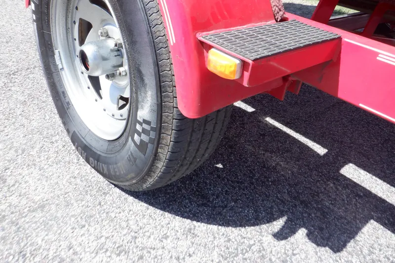 Slide: The Image of Red trailer wheel of 2003 Glastron SX 195 on asphalt surface. - 26