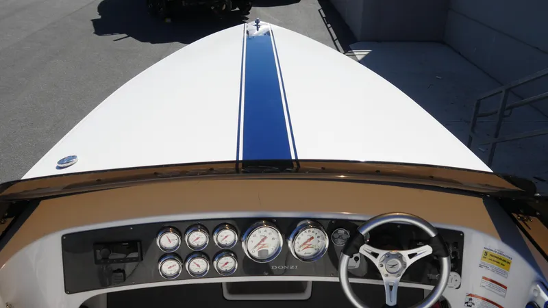 Slide: The Image of 2022 Donzi 22 Classic boat dashboard with gauges and steering wheel, featuring a blue stripe. - 12