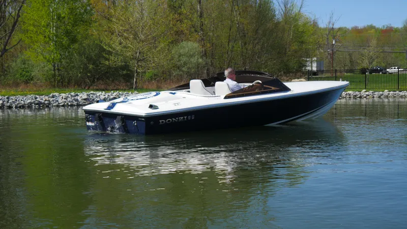 Slide: The Image of 2022 Donzi 22 Classic boat cruising on a calm lake with lush greenery. - 20