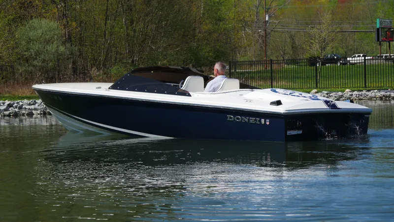 Slide: The Image of 2022 Donzi 22 Classic boat cruising on a calm lake with trees in the background. - 21
