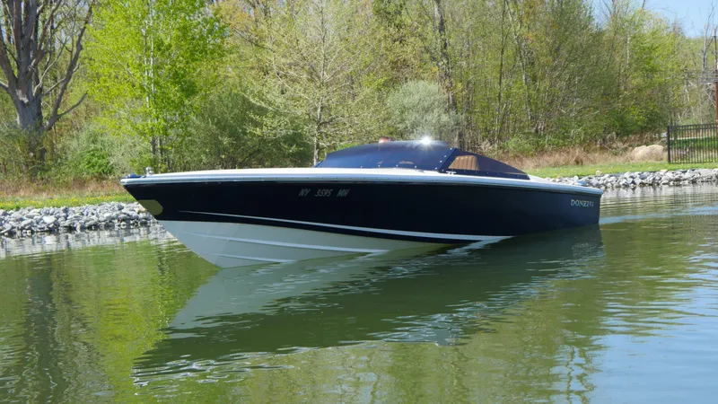 Slide: The Image of 2022 Donzi 22 Classic boat on calm water, surrounded by lush greenery. - 23