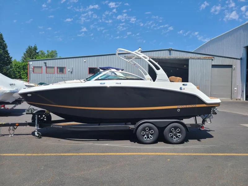 Slide: The Image of 2023 Four Winns HD3 boat on trailer, parked outdoors near industrial buildings. - 1