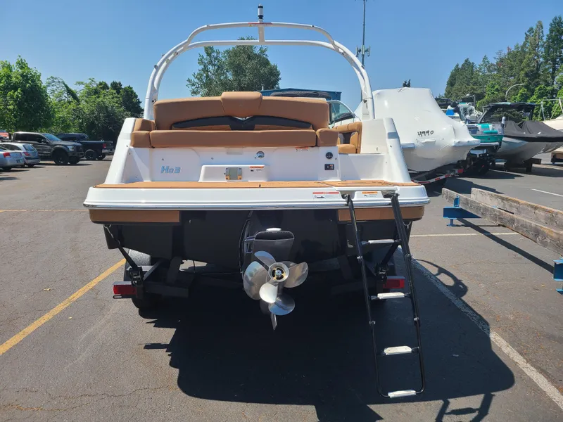 Slide: The Image of 2023 Four Winns HD3 boat, rear view with ladder and propeller, parked outdoors. - 7