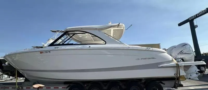 Slide: The Image of 2023 Regal LX36 boat on trailer, side view, outdoors. - 2