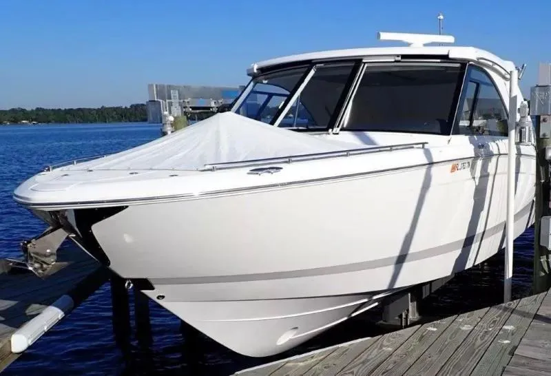 Slide: The Image of 2023 Regal LX36 boat docked by a serene lake under clear blue skies. - 4